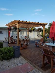 a wooden deck with tables and chairs and a pergola at Lakeview Resort Motel in Wasaga Beach