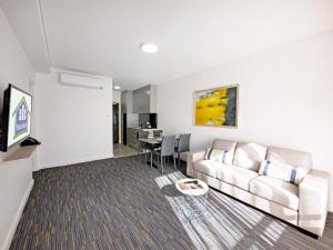 a living room with a couch and a table at Value Suites Penrith in Penrith