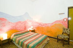 1 dormitorio con 1 cama con una pintura en la pared en Casa Pueblo Hostel en Mendoza