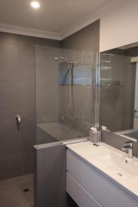 uma casa de banho com uma cabina de duche em vidro e um lavatório. em Just triggin em Perth
