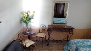 Zimmer mit einem Tisch mit einer Vase aus Blumen und einem Spiegel in der Unterkunft Hotel Posada Maria Bonita in Bernal