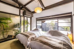 two beds in a room with windows and plants at Nihon Iro in Shizuoka +130 photos
