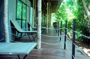 a porch with a rope fence and chairs and trees at Kottawatta Village in Udawalawe
