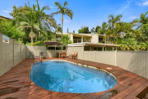 a swimming pool on a wooden deck next to a house at Le Court Villas in Noosa Heads