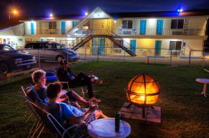 eine Gruppe von Menschen, die neben einem Feuer auf Stühlen sitzen in der Unterkunft Roadrunner Lodge Motel in Tucumcari