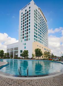 a building with a swimming pool in front of a building at Muong Thanh Luxury Ca Mau Hotel in Cà Mau