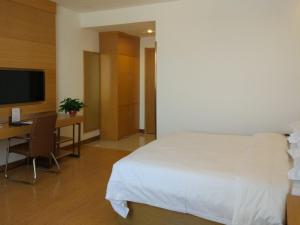 Dormitorio con cama, escritorio y TV en GreenTree Inn Jinzhong Yuci District North Huitong Road Express Hotel, en Jinzhong
