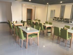 a dining room with tables and green chairs at Vatica Xingtai Qiaoxi District Yongkang Street Technical College Hotel in Xingtai