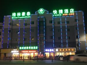 a building with neon signs in front of it at GreenTree Inn Jinzhong Yuci District North Huitong Road Express Hotel in Jinzhong