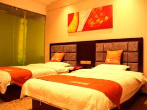 1 Schlafzimmer mit 2 Betten mit orangefarbener und weißer Bettwäsche in der Unterkunft Shell Zhangye Ganzhou Area East Street Drum Tower Hotel in Zhangye