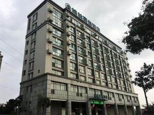 a tall building with a green sign in front of it at GreenTree Inn Yancheng Tinghu Area Wanda Square Hotel in Yancheng