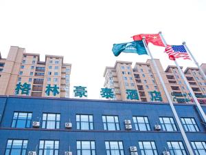 duas bandeiras estão voando em cima de um edifício em GreenTree Inn Yancheng Funing Experimental Primary School Suzhou Road Hotel em Dengshe