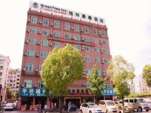 duży różowy budynek z drzewem przed nim w obiekcie GreenTree Inn Jinhua Railway Station Express Hotel w mieście Jinhua