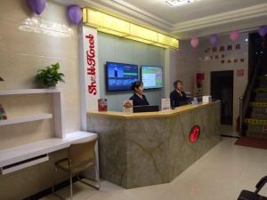 dos personas sentadas en un mostrador en una tienda en Shell Zhangye Ganzhou Area East Street Drum Tower Hotel, en Zhangye
