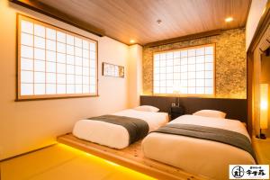 two beds in a room with two windows at Konjaku-So Dotonbori Penthouse Stay in Osaka