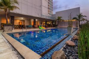 a swimming pool with blue tiles in a building at The Square Surabaya Hotel in Surabaya
