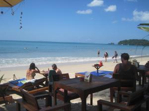 a group of people sitting at tables on the beach at JJ Beach Resort & JJ Seafood in Ko Phayam