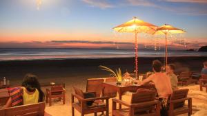 a group of people sitting at a table on the beach at JJ Beach Resort & JJ Seafood in Ko Phayam