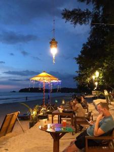 a group of people sitting at tables on the beach at night at JJ Beach Resort & JJ Seafood in Ko Phayam