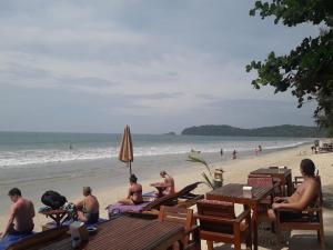 a group of people sitting at tables on the beach at JJ Beach Resort & JJ Seafood in Ko Phayam