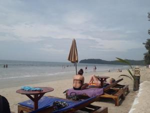two people sitting on the beach under an umbrella at JJ Beach Resort & JJ Seafood in Ko Phayam