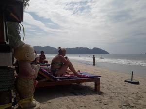 a group of people sitting on a bench on the beach at JJ Beach Resort & JJ Seafood in Ko Phayam