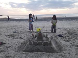 two girls standing in front of a sand castle on the beach at JJ Beach Resort & JJ Seafood in Ko Phayam
