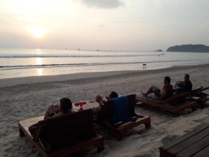 a group of people sitting on the beach watching the sunset at JJ Beach Resort & JJ Seafood in Ko Phayam