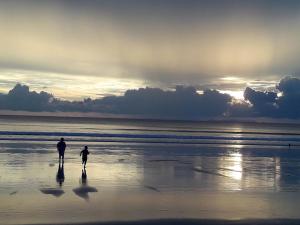 two people walking on the beach at sunset at JJ Beach Resort & JJ Seafood in Ko Phayam