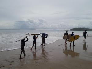 a group of people holding their surfboards on the beach at JJ Beach Resort & JJ Seafood in Ko Phayam