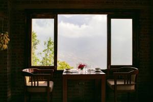 a table and chairs in a room with a large window at Chapa Ecolodge in Sapa