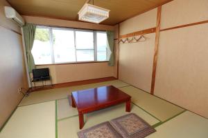 um pequeno quarto com uma mesa e uma janela em Shodoshima Olive Youth Hostel em Shodoshima