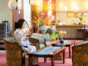 Una donna seduta su una sedia che guarda il suo cellulare di Ogiwarakan a Chikuma