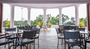 ein Restaurant mit Tischen, Stühlen und Säulen in der Unterkunft Ponderosa Golf & Country Resort in Johor Bahru