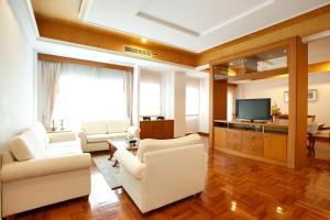 sala de estar con muebles blancos y TV en Chaidee Mansion, en Bangkok