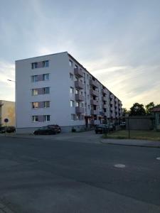 een groot wit appartementencomplex met een parkeerplaats bij Kesklinna Apartement in Haapsalu