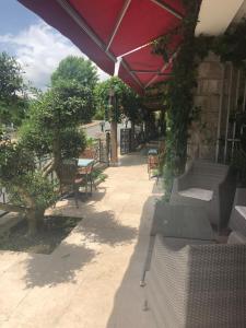 a patio with tables and chairs and an umbrella at Hotel Clair de Lune in Zonza