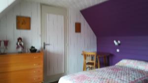a bedroom with purple walls and a bed and a dresser at Chez Mamie in Beynat