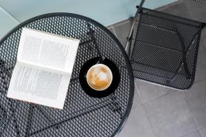 a cup of coffee sitting on a table with a book at Comfort Hotel LT - Rock 'n' Roll Vilnius in Vilnius