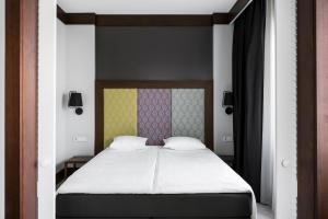 a bedroom with a bed with white sheets and a yellow headboard at Comfort Hotel LT - Rock 'n' Roll Vilnius in Vilnius