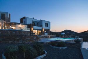 a large house with a swimming pool at dusk at Villa Lina Syros in Azolimnos Syros