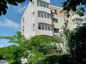 a tall white building with trees in front of it at Apartament Faleza Nord in Constanţa
