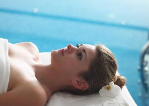 une femme qui se couche sur un lit avec un anneau de fleurs dans l'établissement Grand Serai Congress and Spa, à Ioannina