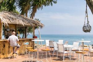 a man sitting at a bar on the beach at Elya Beach Luxury Suites in Ayios Theodhoros