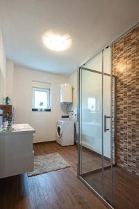 a bathroom with a glass shower and a washing machine at Holiday Home Luma in Grabovica