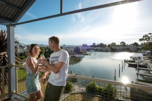 a man and woman standing on a balcony drinking wine at Captains Cove Waterfront Apartments in Paynesville