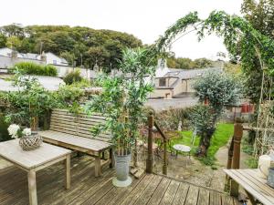 a patio with a wooden table and benches and trees at 19A Kingshead Street in Pwllheli