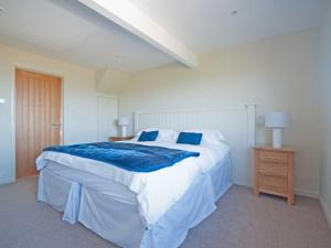 a bedroom with a large bed with blue and white sheets at Crantock Bay House in Crantock