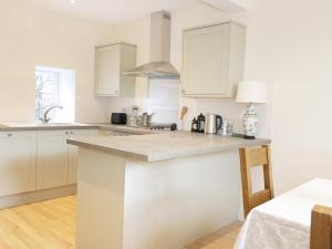 a kitchen with white cabinets and a counter top at The Grieves Cottage in Haddington