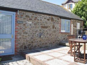 a stone house with a table and a blue door at Millers Cottage in Bude